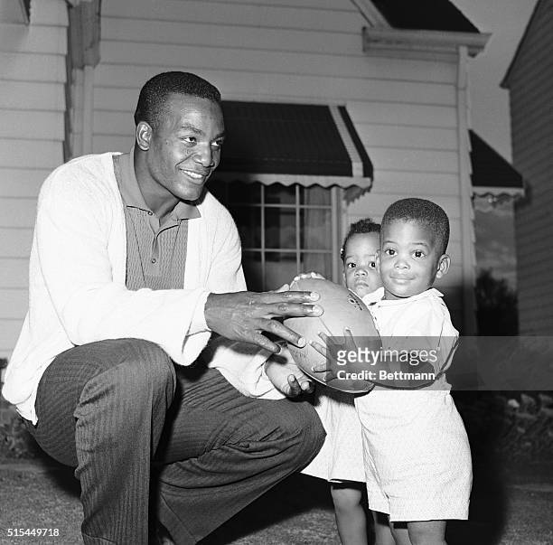 Cleveland, Ohio- Jim Brown, fullback of the Cleveland Browns, preps his son Kevin for some leather-lugging as Kevin's twin sister, Kim, looks on....