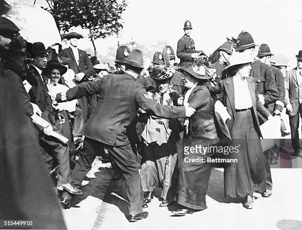 Police prevent suffragist Emmeline Pankhurst and her two daughters Chistabel and Sylvia from entering Buckingham Palace to present a petition to the...