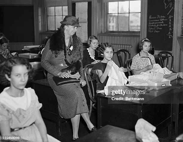 Washington, D.C.- Mrs. Franklin D. Roosevelt, shows a great deal of interest in the work of the sewing class of the Alice Deal Junior High School....