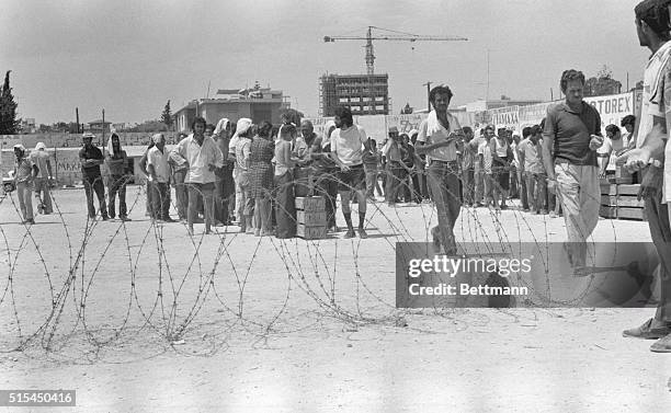 Limassol, Cyprus-Behind an improvised fence of barbed wire, Turkish-Cypriot prisoners line up for food issued to them at the Limassol Football...
