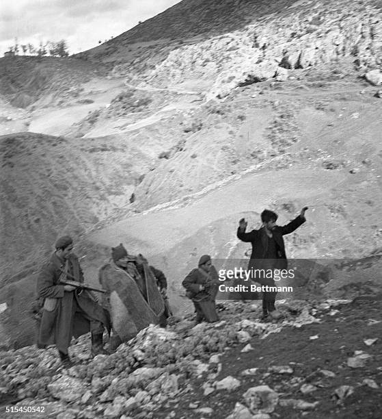 Northern Greece- With arms raised, a guerrilla sniper is led up a snow-covered mountain trail by Greek Army troops who captured him during mopping up...