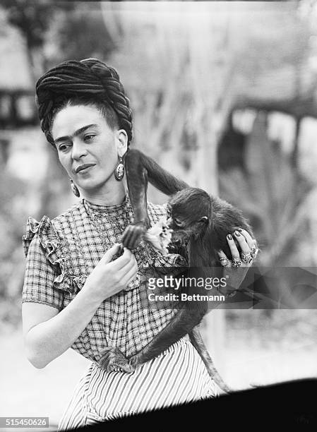 Photograph of Frida Kahlo , Mexican painter, holding a monkey. She is the wife of Diego Rivera.