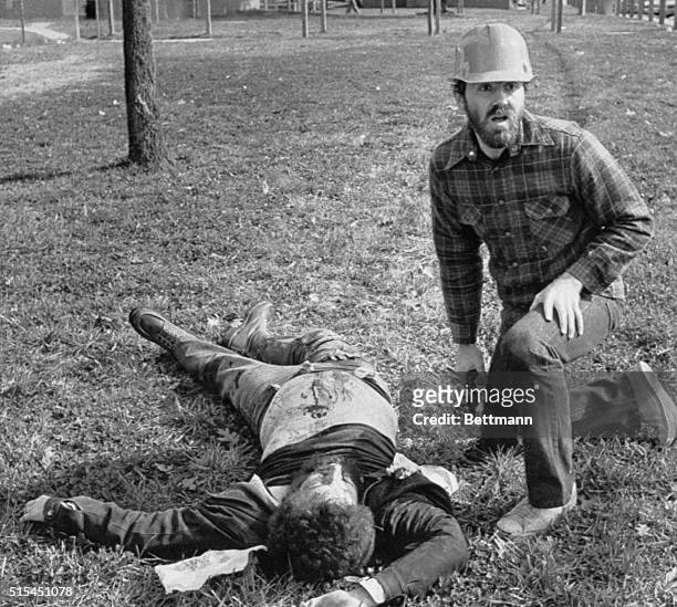 Greensboro, North Carolina- A pistol-carrying comrade kneels beside a slain member of the Communists Workers Party, Nov.4 only moments after a...