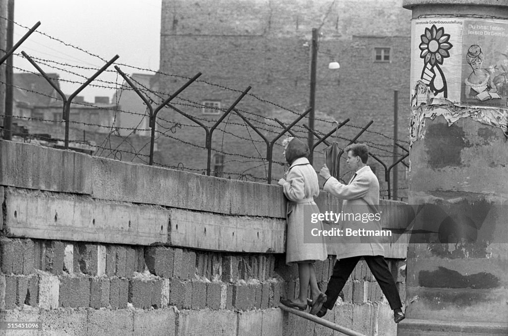 Young Couple Peers Over Berlin Wall