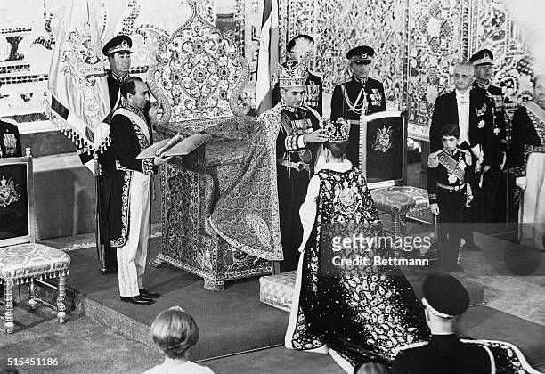 Teheran, Iran- With Crown Prince Reza watching at right, the Shah of Iran places a crown on his wife, Queen Farah, after crowning himself in a lavish...