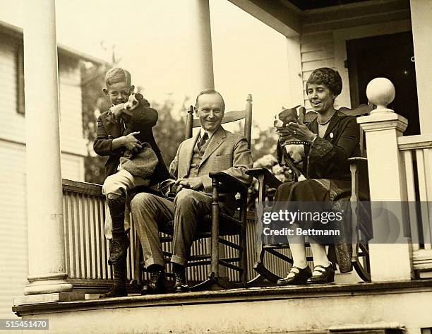 Northampton, MA-President Calvin Coolidge is shown with his wife Grace, some dogs and a neighbor's child on the porch of the Northampton, MA, home....