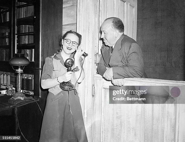 Boston, MA-Alfred Hitchcock , noted film director, smiles as he watches his daughter Pat answer the phone during rehearsal for "Violet," in which she...