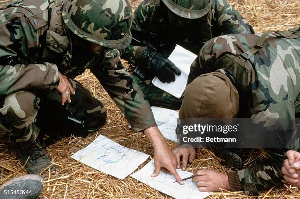 Grenada: United States combat soldiers pour over maps on the ground during the United States invasion of the island of Grenada.