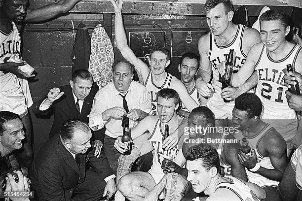 The victorious Boston Celtics, NBA basketball champions for the fourth consecutive year, whoop it up in the dressing room, flanking their coach Red...