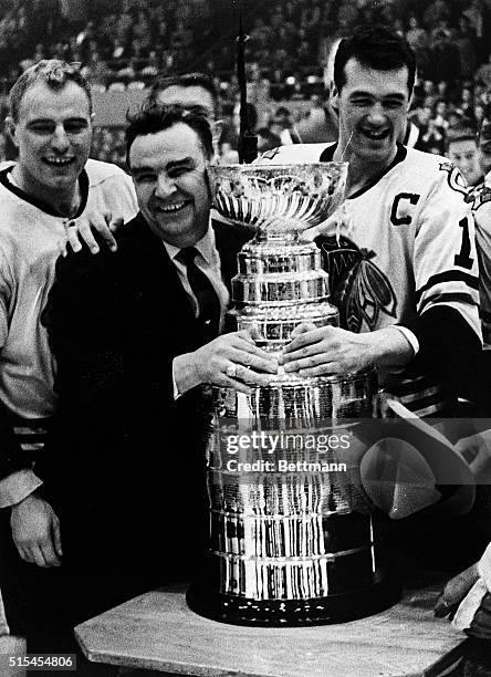 Detroit, Michigan-: Happily embracing the Stanley Cup after his Blackhawks won it by defeating the Detroit Red Wings is coach Rudy Pilous as players...