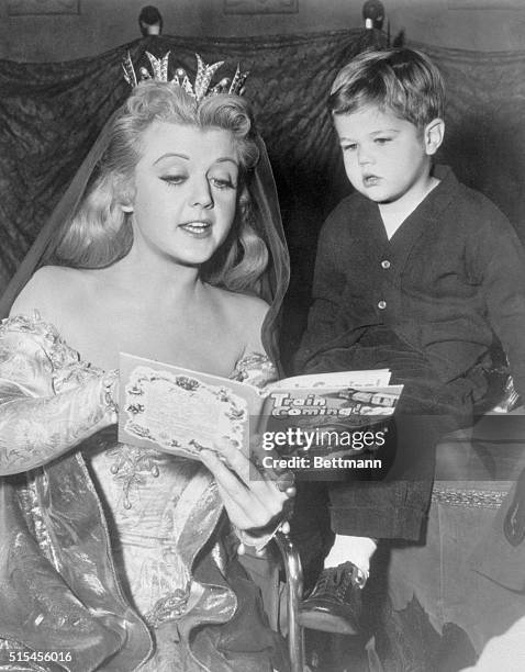 Looking like something out of a fairy tale, film star Angela Lansbury amuses a tiny visitor, her son, Michael, by reading a modern fairy tale during...