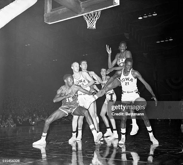 Iowa Hawkeyes and San Francisco Dons have varied expressions as they watch the ball fly loose during tussle under the basket in the first half of...