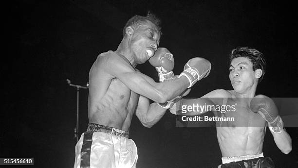 Flash Elorde of the Philippines delivers a hard right to the face of featherweight champion Sandy Saddler during their title bout at the Cow Palace....