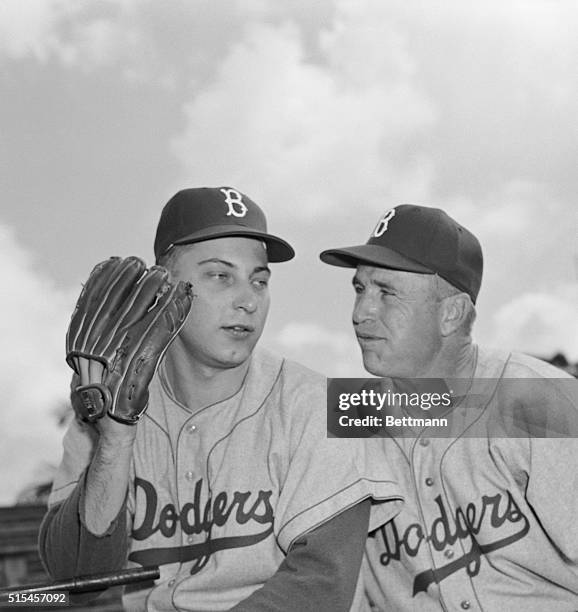 Dodger pitcher Johnny Podres, last year's World Series hero, holds a whispered conversation with manager Walter Alston, after reporting to the Dodger...
