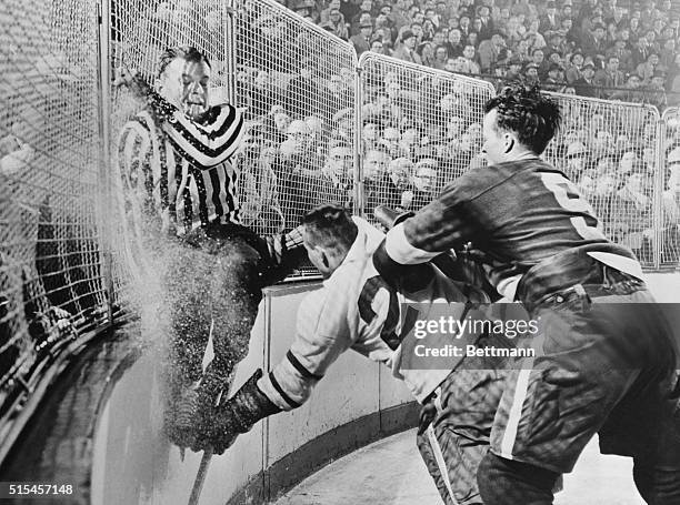 Frank Udvari, tries to get out of harm's way as Red Wing Gordie Howe sends Toronto's Gordie Hannigan into the boards during semifinal Stanley Cup...