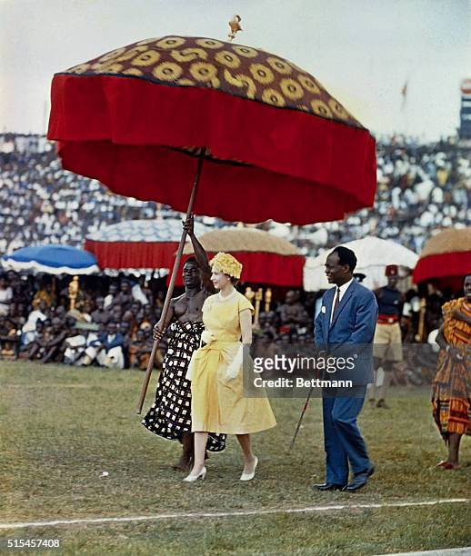 Ghana: Queen Elizabeth II makes her way underneath a large, gaily colored umbrella, to a dais to watch the Durbar of the Ashanti Chiefs, at Kumasi...