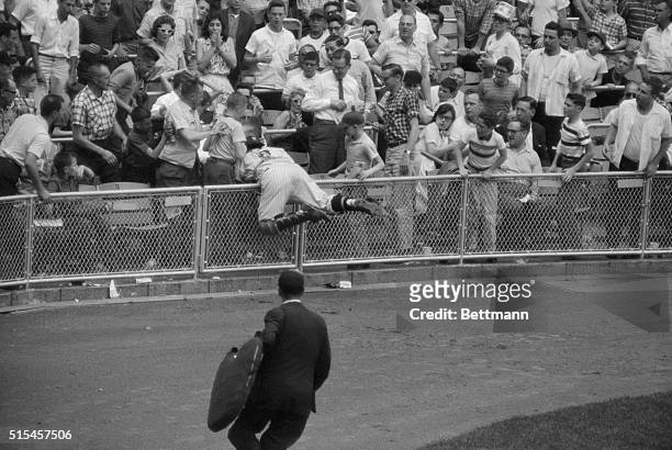 Upended Yankee catcher Yogi Berra dives into the stands for futile try for Boston's Ed Sadowski's pop fly in the 7th inning of first of two games...