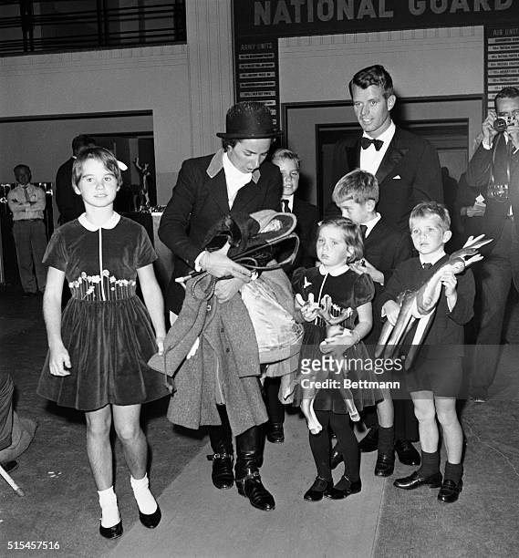 Gathering their coats in her arms, Mrs. Robert Kennedy rounds up husband and children after participating in the International Horse Show at the...