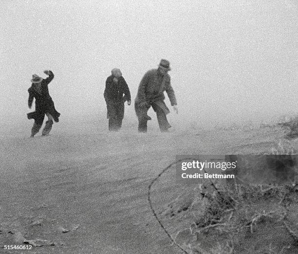 Men walk through a dust storm in Garden City, Kansas during the Dust Bowl. Agricultural damage caused by deep plowing, no crop rotation and lack of...