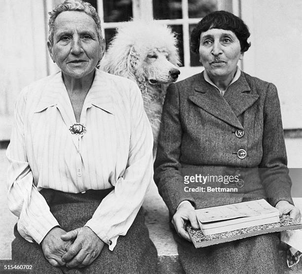 Gertrude Stein, one of the world's foremost novelists, poses with Alice B Toklas, and her dog, Basket, in front of her home in France. The grand lady...