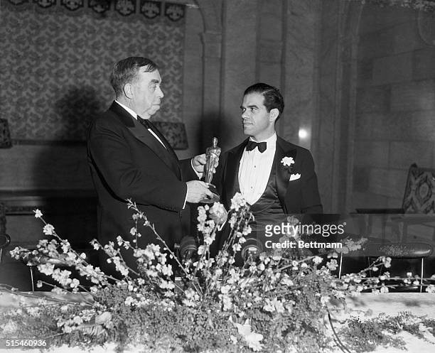 Hollywood, CA: Irvin Cobb presents the statuette to Frank Capra, on behalf of the Academy of Recording Arts and Sciences, for Best Direction for his...