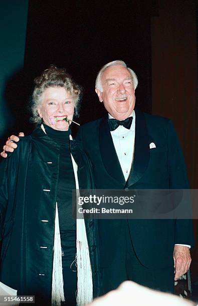 Clutching a rose, that Walter Cronkite gave her, in her teeth, Katharine Hepburn smiles for the crowd after the dual tribute to herself and her...