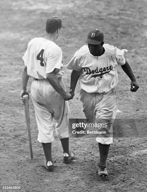 Jackie Robinson of the Dodgers is congratulated here by teammate Pete Reiser as he scored on his homer in the 1st inning of an afternoon game at...