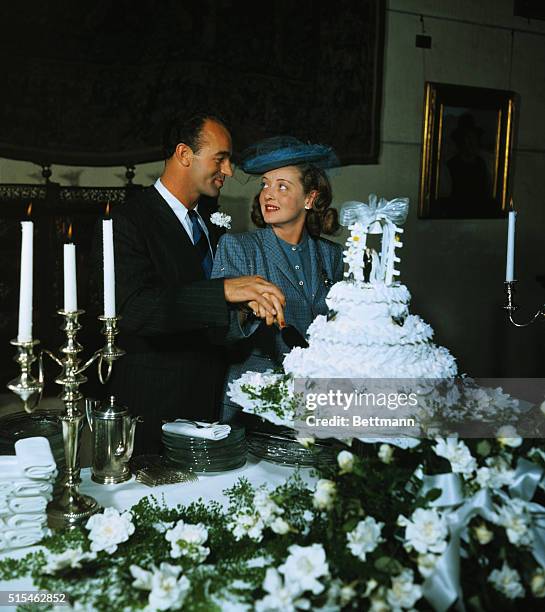 Screen Star Betty Davis and William Grant Sherry are photographed immediately after their marriage this afternoon as they cut their wedding cake. The...