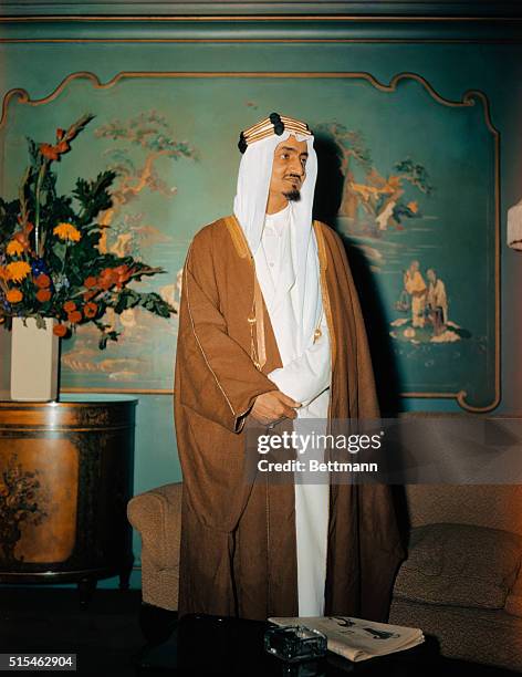 Prince Emir Faisal, second son of King Ibn Saud of Saudi Arabia, is shown standing in front of a painting.