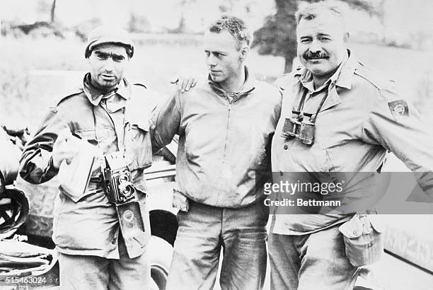 Robert Capa, left, photographer for Life magazine and Ernest Hemingway, right, stand with an unidentified soldier in this undated photo.
