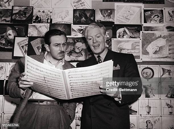 American film producer and creator of Disney World, Walt Disney, holds sheet music with actor Eddy Nelson.