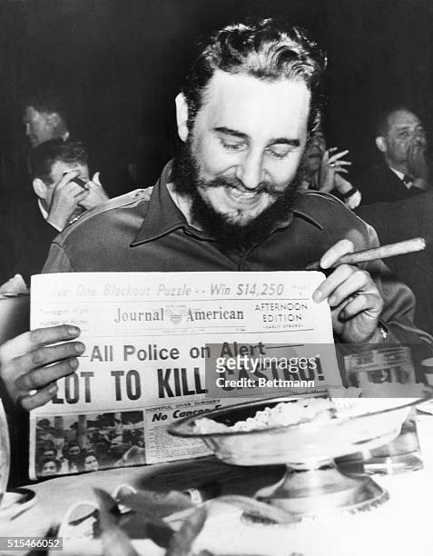 Seems amused by assassination plot...Seeming quite amused, Cuban Prime Minister Fidel Castro holds up a newspaper headlining the discovery of a plot...