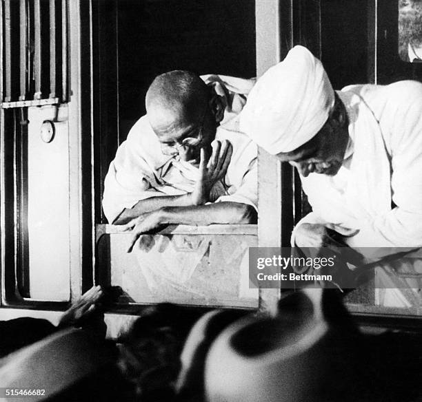 Notable Indian political figure Mahatma Gandhi peers down at a crowd from a window.