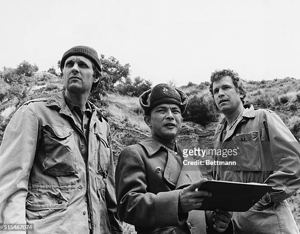 Alan Alda, as Hawkeye, and Wayne Rogers as Trapper John face a rather nerve-racking roadblock when they are stopped by Red Chinese Dr. Tam, played by...
