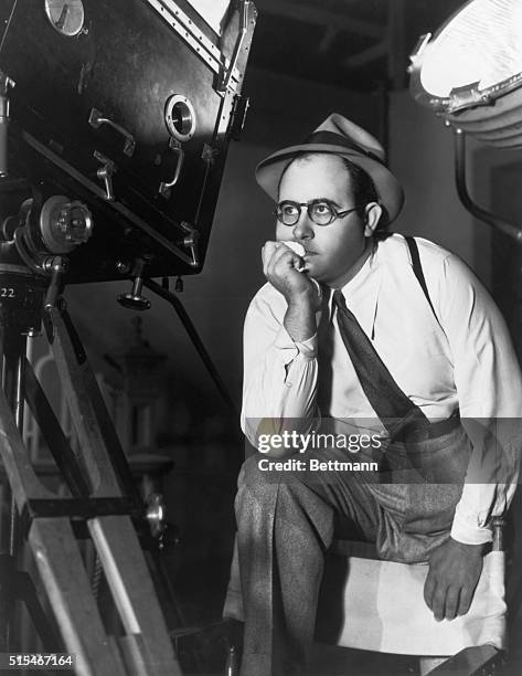 Norman Taurog, American movie director, shown behind the camera with one leg on his director's chair.