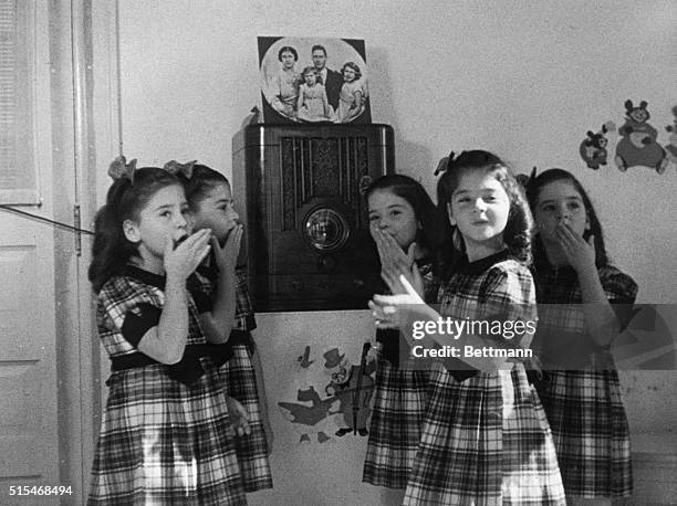 The Dionne quintuplets gathered around a radio listening to Queen Elizabeth speaking to children of the Empire who were sent overseas to wartime...