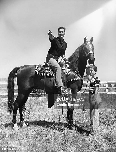 Errol Flynn and his son, Sean, 9. Errol enjoys a ride around his estate grounds. He will soon be seen in Warner Brothers' Rocky Mountains.