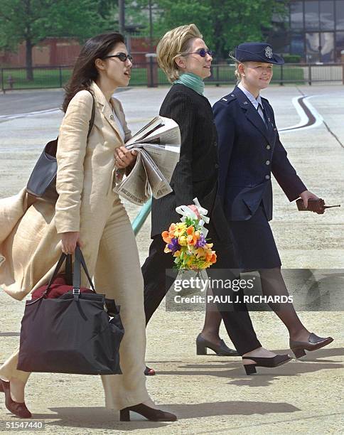 First Lady and New York Senate candidate Hillary Clinton carries flowers and is led by an unidentified Andrews Air Force Base Protocol Officer while...