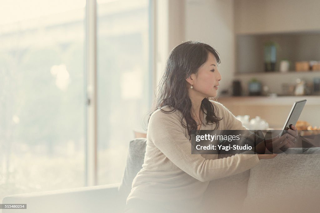 Women using digital tablet and sitting on the sofa