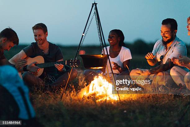 amigos em torno da fogueira de acampamento - fogueira de acampamento imagens e fotografias de stock