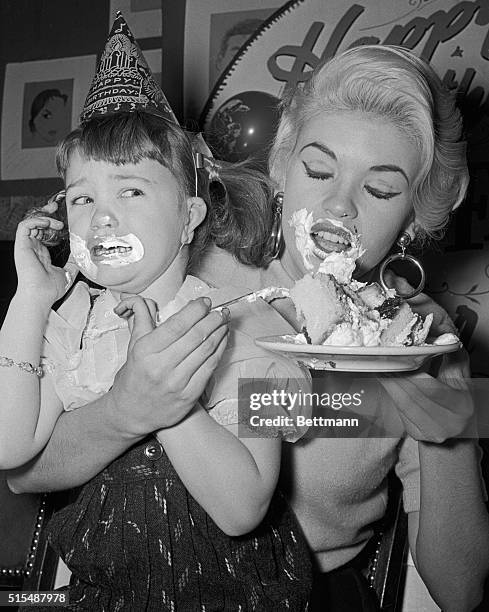 Creamy topping is all over the faces of stage star Jayne Mansfield and daughter Jayne Marie as they eat birthday cake at a party for theater folks...