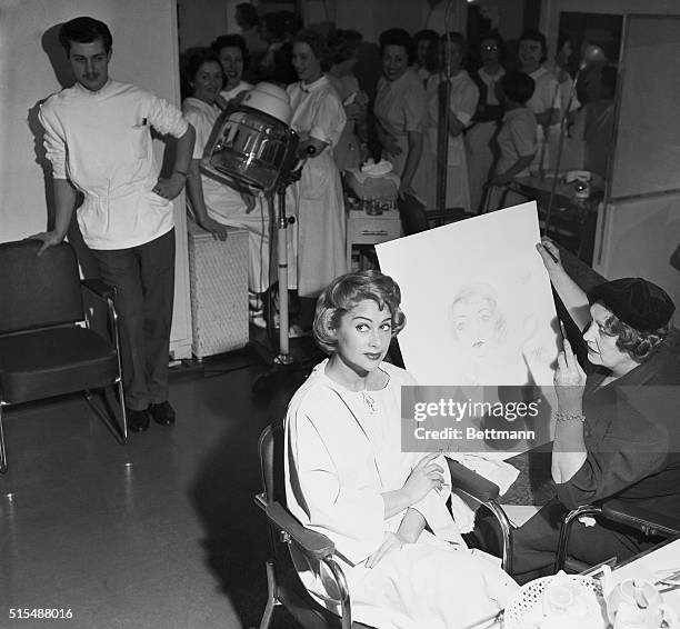 Getting a beauty treatment in pencil and in person at the same time, lovely French actress Martine Carol poses for an artist in a Paris beauty shop....