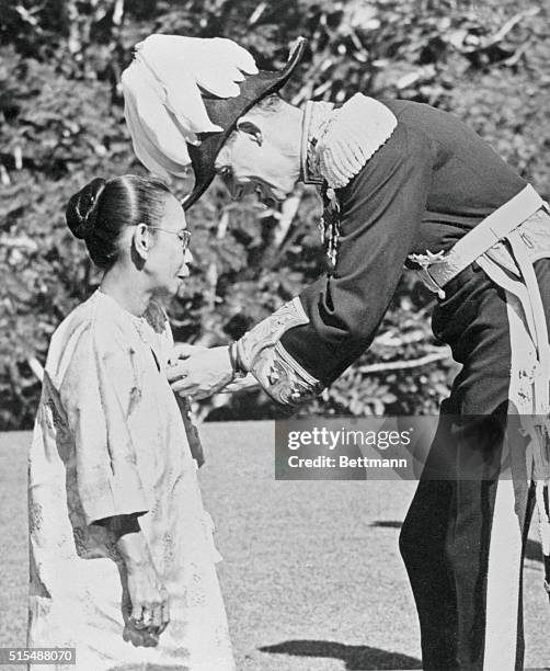 British High Commissioner in Malaya, Sir Donald MacGillivray, bestows upon Datin Shariffah Hawa Binti Khalid , matron of the King's House here, the...