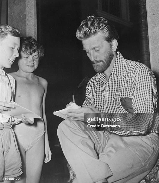 Kirk Douglas, sporting a handsome chine growth, obliges young admirers with his autograph in Venice, where he is among many Hollywood celebrities...