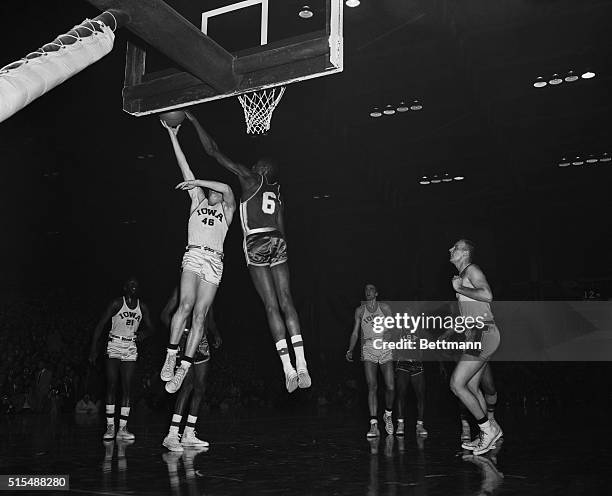This is an action shot during a NCAA Basketball Tournament final, as Bill Russell, , blocks attempted shot by Milt Scheuerman of Iowa.