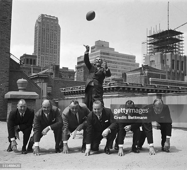 With club officials and coaches lined up in front of him, Slingin' Sammy Baugh, head coach of the New York Titans, warms up his throwing arm at a...