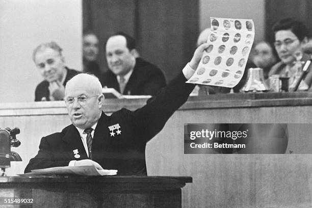 Moscow: Appearing before the Soviet Parliament, Soviet Premier Nikita Khrushchev holds aloft photos which he identified as views of Military and...