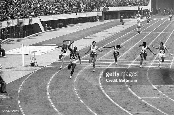 Bob Hayes of the US gleefully tosses the baton high in the air as he snaps the tape ahead of M. Dudziak of Poland, to win the 400 meter relay in the...