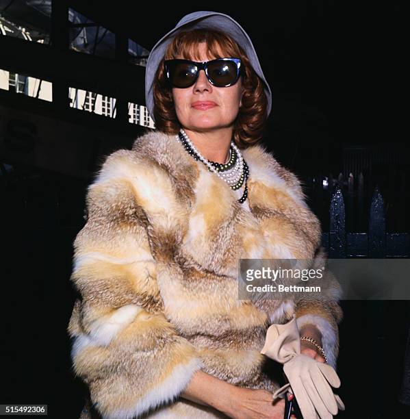 Rita's back. New York. Bedecked in furs and several strands of beads, actress Rita Hayworth takes off her sunglasses for the photographers, as she...