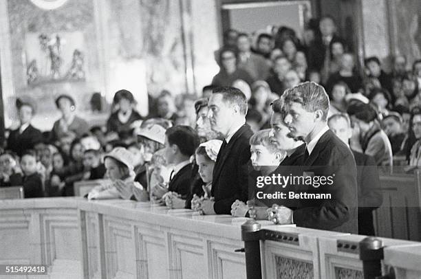 Senator-elect and Mrs. Robert Kennedy and Peace Corps director and Mrs. R. Sargent Shriver kneel at the communion rail with their children during a...